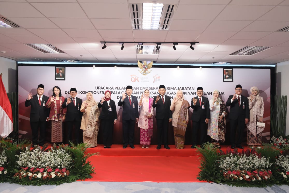 A group of officials in formal attire poses for a photo at a ceremony, with a backdrop featuring the Indonesian flag and emblem.